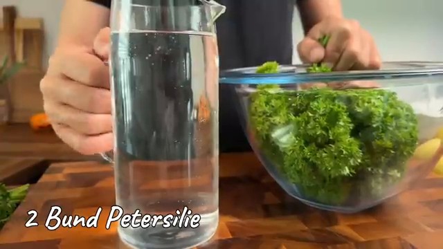 Rinçage minutieux des bottes de persil frais dans un grand récipient d'eau