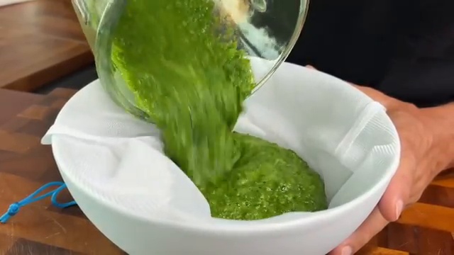Filtrage du jus vert épais à travers une étamine pour récupérer le liquide pur