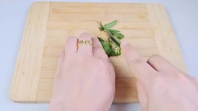Les feuilles de géranium sont hachées finement sur une planche en bois avec un couteau.